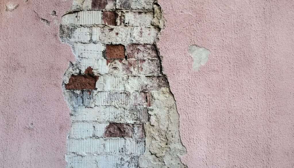 Close-up of peeling paint on an HDB wall, indicating moisture damage. HDB painting services