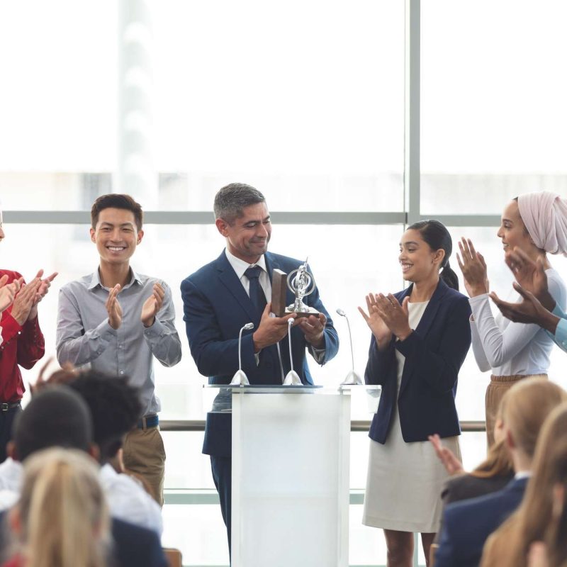 businessman-holding-award-on-podium-with-colleagues-at-business-seminar.jpg businessman-holding-award-on-podium-with-colleagues-at-business-seminar.jpg